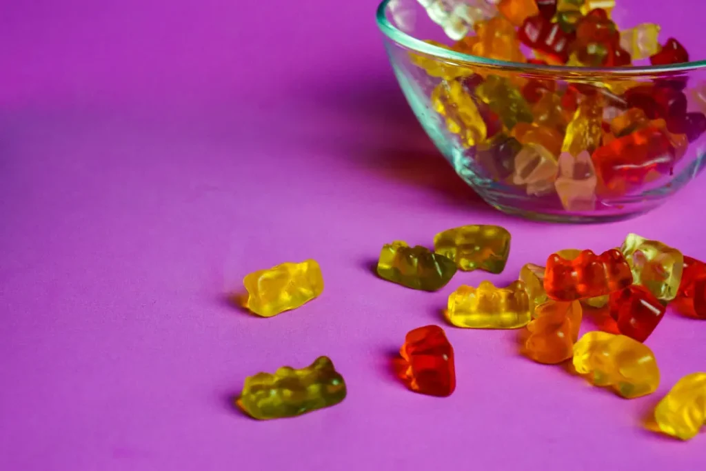  some gummy bears on pink background and in a bowl