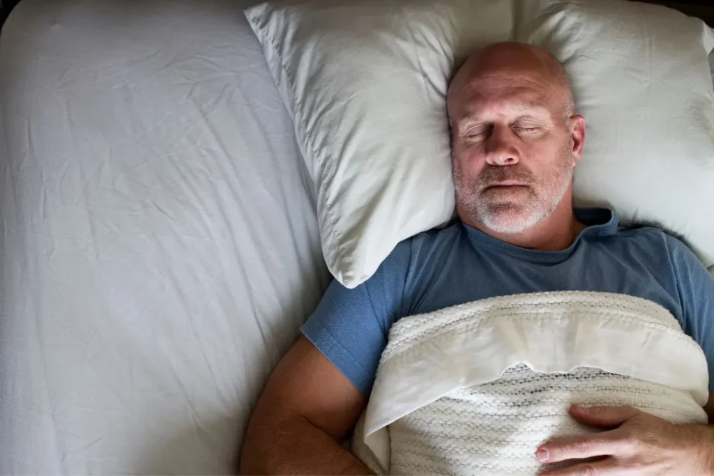 An old man sleeping on the bed.  