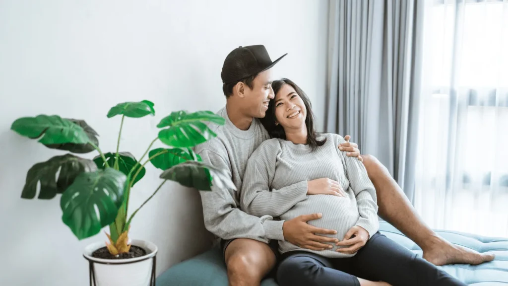 Pregnant woman sitting on her husband lap