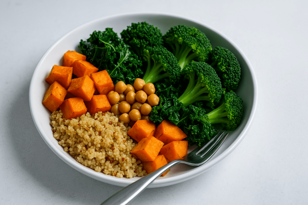 Healthy Plant-Based Dinners Made Easy: Best Whole Food Plant-Based Recipes for Beginners and Beyond 2 A white bowl filled with a vibrant whole food plant-based meal sits on a clean white surface under cool clinical lighting, emphasizing the freshness and color of each ingredient. The dish features neatly arranged quinoa, roasted sweet potatoes, chickpeas, kale, and broccoli, visually reinforcing the simplicity and nutritional balance of healthy plant-based dinners made easy.