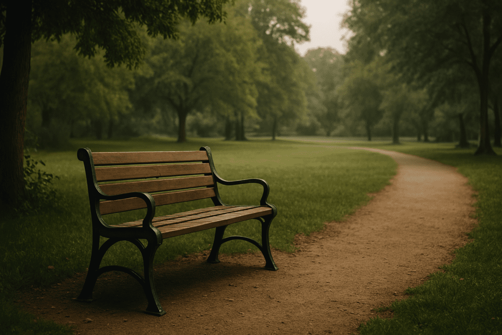 How a Vegan Diet Can Help Reverse Heart Disease: What the Science Says 3 A wooden park bench with black metal armrests sits beside a winding dirt path, surrounded by lush green grass and trees in the background. Soft daylight filters through the foliage, creating a calm outdoor ambiance.