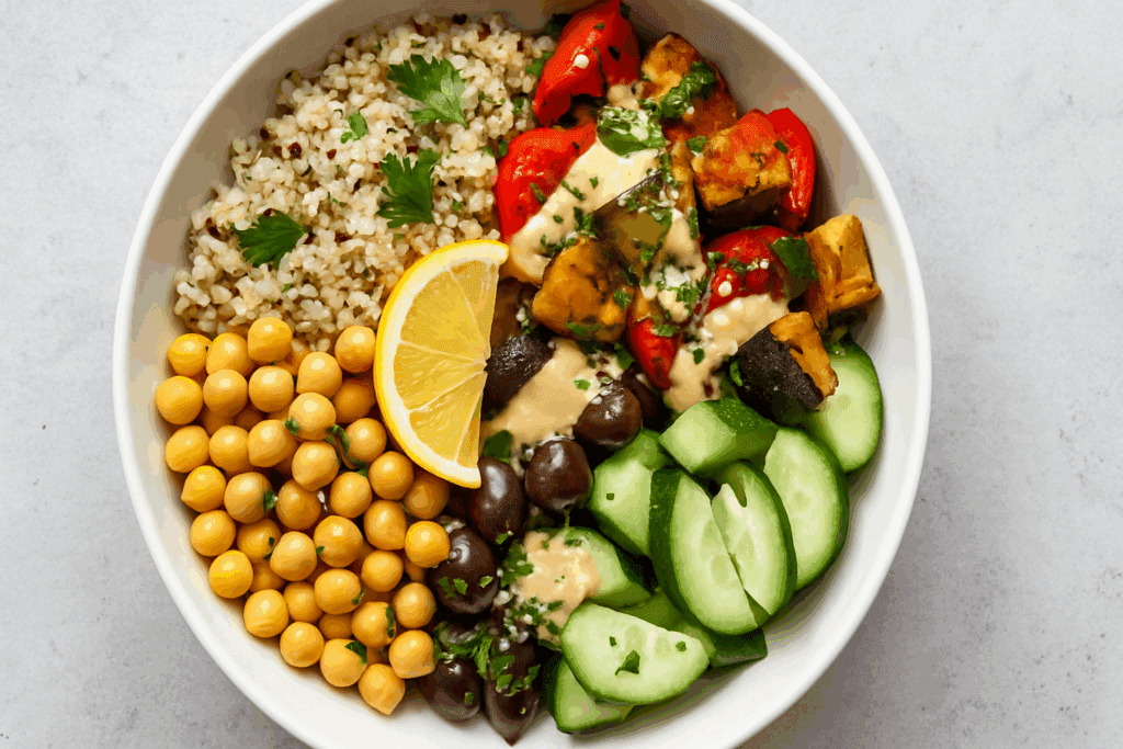 Overhead view of a Mediterranean grain bowl with quinoa, chickpeas, cucumbers, olives, and roasted vegetables—an example of non bread lunch ideas.